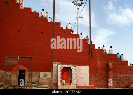 La gente siede sulle scale davanti ad un vecchio edificio a Varanaside, dentro Foto Stock
