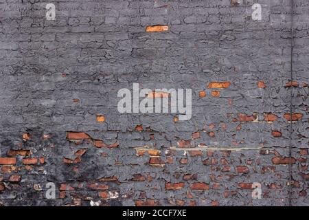 Vernice grigio ardesia, invecchiamento e desquamazione di mattoni rosso-arancio su una parete esterna di un edificio di appartamenti a New York City Foto Stock