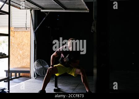 Giovane uomo che lavora fuori con i manubri in un garage Foto Stock