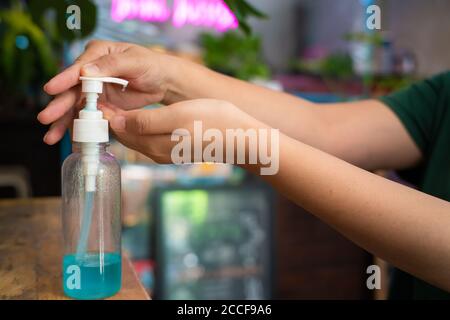 Donne sanitizzante per le mani gel di alcol pulizia per le mani prevenzione dell'igiene focolaio del virus del coronavirus prima di entrare in negozio Foto Stock