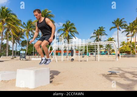 Jump box di allenamento uomo atlhete salto facendo forza allenamento fuori in spiaggia calisthenics parco a South Beach, Miami, Florida Foto Stock
