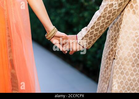 Una coppia indiana di nozze che tiene le mani dopo la cerimonia nuziale Foto Stock