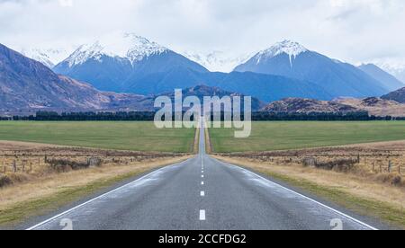 Vista panoramica della lunga strada ghiacciata rettilinea che conduce verso Montagne nell'isola meridionale della Nuova Zelanda Foto Stock