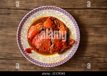 Granchio in salsa Padang o granchio Padang (indonesiano: Kepiting saus Padang) su sfondo di legno. Foto Stock