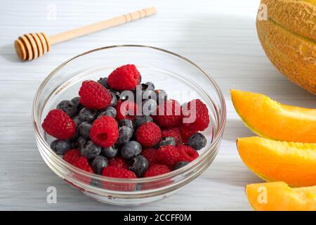 Vista ad alto angolo della ciotola con frutti di bosco e affettati melone arancione Foto Stock