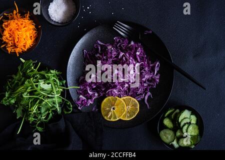 Salutare concetto di insalata con verdure crude e fresche in un ciotola su fondo nero di cemento Foto Stock