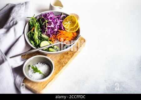 Salutare concetto di insalata con verdure crude e fresche in un ciotola su fondo di cemento Foto Stock