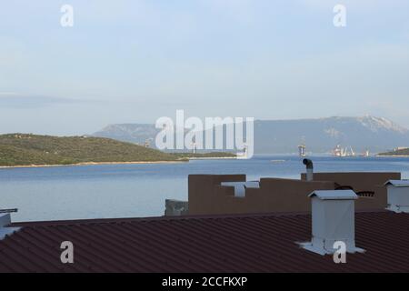 Tetti e camini e una vista sul mare Adriatico Verso la Croazia dove si può vedere il ponte Peljesac sotto costruzione Foto Stock