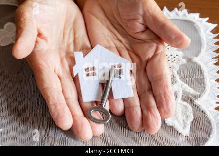 Vecchia donna che tiene il modello della casa e la chiave della casa in hand.Mortgage prestito di approvazione del prestito domestico e concetto di assicurazione Foto Stock