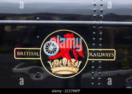 Un primo cresta delle ferrovie britanniche su ex-GWR 0-6-0 pannier tank steam loco 7714 presso la stazione di Minehead, West Somerset Railway Spring Gala, Inghilterra, Regno Unito Foto Stock