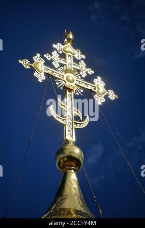 = Croce Ortodossa dorata splendente = splendente al sole Croce ortodossa sulla cima di una cupola della chiesa dedicata Alla Natività della Beata Vergine Maria in S. Foto Stock