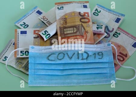 La maschera protettiva facciale con testo covid-19 si trova su molte banconote da 50 e 10 euro di closeup valuta. Foto Stock