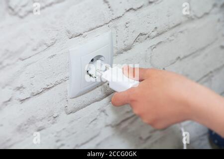 collegare il caricabatterie a una presa a muro. Risparmia energia: Scollegare il caricabatterie. Foto Stock
