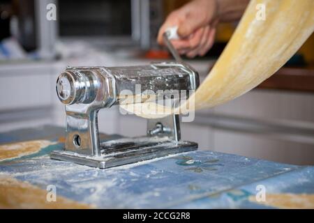 In cucina, preparazione della pasta fatta in casa con la macchina per la pasta. Foto Stock