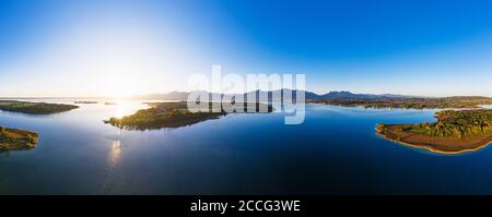 Panorama dal Lago di Chiemsee all'alba, Herreninsel e la penisola di Sassau, Chiemgau, vista aerea, alta Baviera, Baviera, Germania Foto Stock