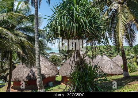 Bungalow con tetto in paglia e costruito nel vecchio tradizionale strada su una riva del mare con giungla intorno alla zona In Axim Ghana Africa occidentale Foto Stock