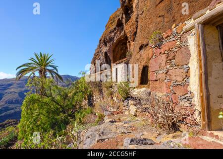 Case abbandonate sotto muro di roccia, Tacalcuse, vicino a San Sebastian, la Gomera, Isole Canarie, Spagna Foto Stock