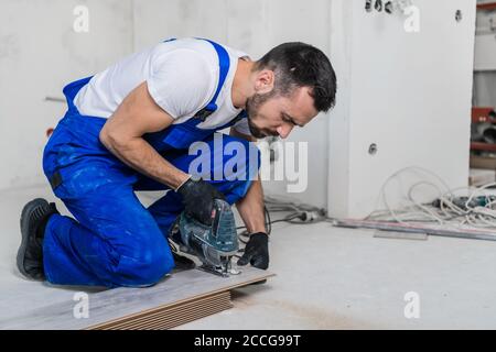 Uomo da lavoro in laminato con taglio uniforme blu e seghetto alternativo. Scatto medio Foto Stock