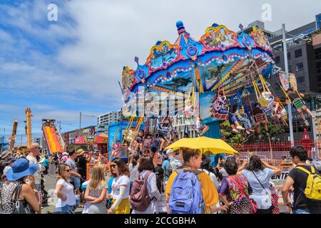Giostre di Carnevale. Bambini su una giostra swing, circondato da una grande folla. Fotografato ad Auckland, Nuova Zelanda, 1/27/2019 Foto Stock
