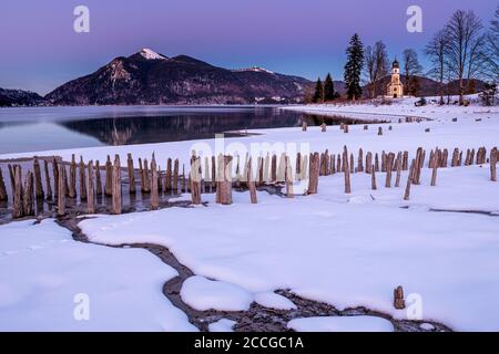 La piccola cappella di San Margareth, Jochberg sullo sfondo e in primo piano le antiche tavole di legno di una storica fattoria di pesce o gamberi su t Foto Stock