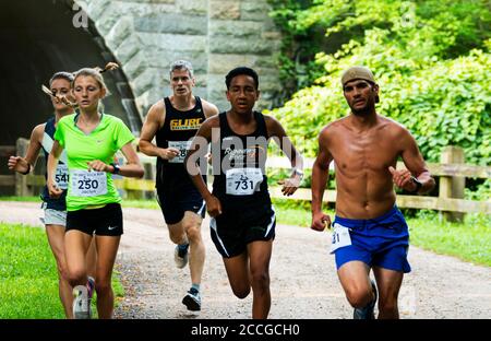 Babylon, New York, USA - 12 agosto 2018: I corridori veloci che emergono da sotto il tunnel durante la gara di pista 10K della calza sporca. Foto Stock