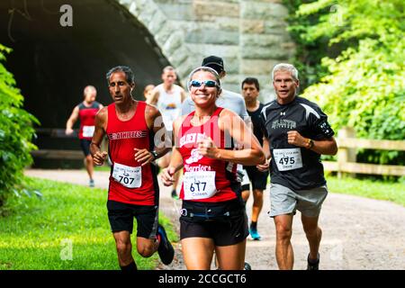 Babylon, New York, USA - 12 Agosto 2018: Donne che sorridono alla macchina fotografica dopo aver eseguito il nostro tunnel durante la gara di pista sporca calzino 10K. Foto Stock