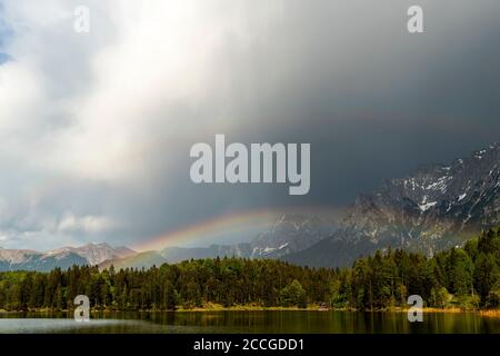 Arcobaleno dopo la tempesta a Lautersee vicino a Mittenwald nelle Alpi bavaresi. Sullo sfondo le nuvole e le montagne del Karwendel Foto Stock