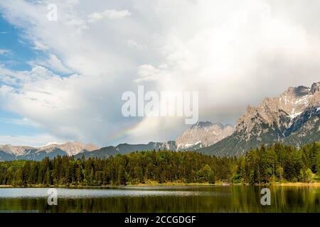 Arcobaleno dopo la tempesta a Lautersee vicino a Mittenwald nelle Alpi bavaresi. Sullo sfondo le nuvole e le montagne del Karwendel Foto Stock