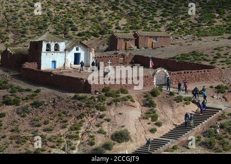 I turisti visitano la chiesa di adobe nel remoto villaggio delle Ande cilene di Machuca. Foto Stock