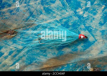 Una vecchia mosca di salmone dotata di un gancio di acuti preso da una scatola di mosca, o serbatoio. Visualizzato su un pezzo di driftwood. Da una collezione di pesca tac Foto Stock