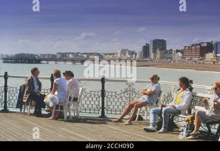 Turisti sul molo del Palazzo con il molo ovest sullo sfondo. Brighton, East Sussex, Inghilterra, Regno Unito. Circa anni '80 Foto Stock