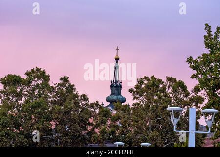 Zrenjanin, Serbia, 05 ottobre 2019. La cima del campanile della chiesa con una croce in cima che sorge in lontananza la sera e il tramonto. Foto Stock