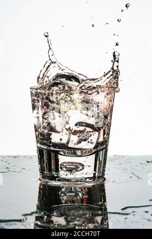 Cubo di ghiaccio che si tuffa in un bicchiere d'acqua - fuoco selettivo. Fotografia ad alta velocità Foto Stock