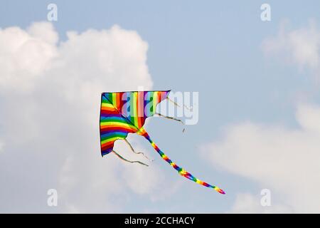 Il giocattolo preferito dai bambini si aquilano nelle giornate ventose in primavera, cielo blu e nuvole bianche. Un aquilone colorato oscilla nel vento. Foto Stock