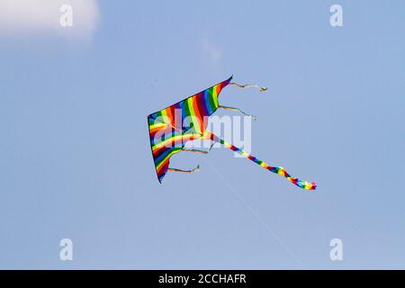 Il giocattolo preferito dai bambini si aquilano nelle giornate ventose in primavera, cielo blu e nuvole bianche. Un aquilone colorato oscilla nel vento. Foto Stock