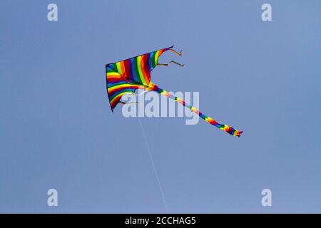 Il giocattolo preferito dai bambini si aquilano nelle giornate ventose in primavera, cielo blu e nuvole bianche. Un aquilone colorato oscilla nel vento. Foto Stock