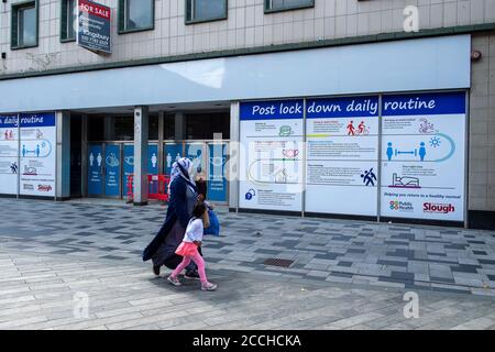 Slough, Berkshire, Regno Unito. 22 agosto 2020. Gli acquirenti passano davanti a un avviso pubblico di routine post-blocco in Slough High Street. Slough in Berkshire è stato nominato dal Public Health England e dal Department for Health and Social Care come una "area di preoccupazione" del Covid-19 a seguito di un recente aumento del numero di casi. Credito: Maureen McLean/Alamy Foto Stock