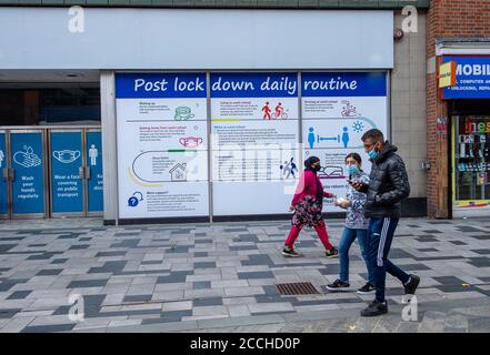 Slough, Berkshire, Regno Unito. 22 agosto 2020. Gli acquirenti passano davanti a un avviso pubblico di routine post-blocco in Slough High Street. Slough in Berkshire è stato nominato dal Public Health England e dal Department for Health and Social Care come una "area di preoccupazione" del Covid-19 a seguito di un recente aumento del numero di casi. Credito: Maureen McLean/Alamy Foto Stock