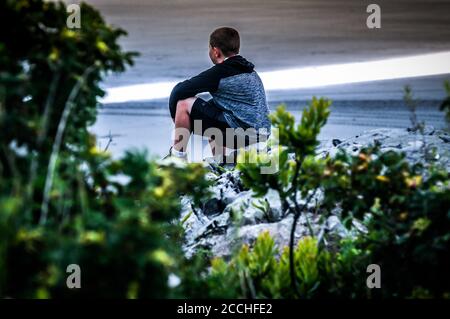 Un ragazzo si siede sulle rocce guardando fuori le nuvole che formano una linea tra il cloud Non molte banche hanno visto una tale linea retta nuvole Foto Stock