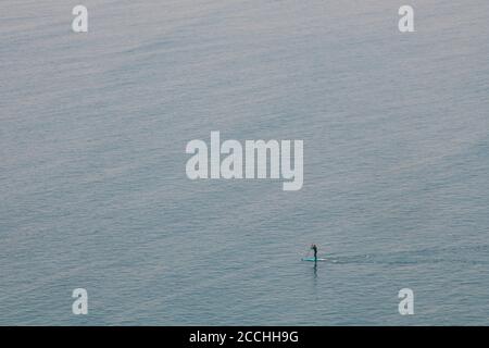 Un solista paddle Boarder nel mare sul Devonshire Costa nell'Oceano Atlantico Foto Stock