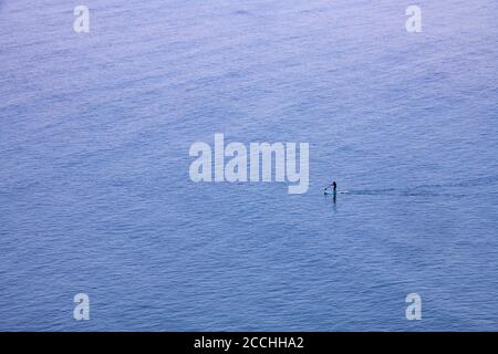 Un solista paddle Boarder nel mare sul Devonshire Costa nell'Oceano Atlantico Foto Stock