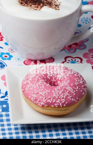 Ciambella di rosa e una tazza di cappuccino Foto Stock