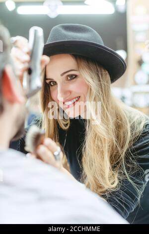 Donna barbiere taglio e taglio barba di cliente nel suo negozio Foto Stock