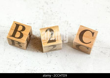 Tre cubetti di legno con lettere B2C (sta per Business to Customer) su lavagna bianca. Foto Stock