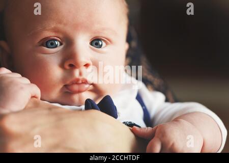 Bambino di quattro mesi sulle mani della madre, dettaglio sul viso e gli occhi blu Foto Stock