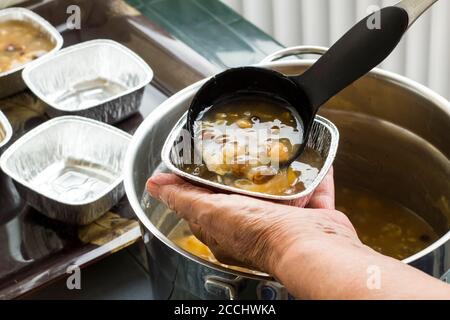 La mano sta servendo il dessert ashura con il mestolo nero, primo piano. Foto Stock