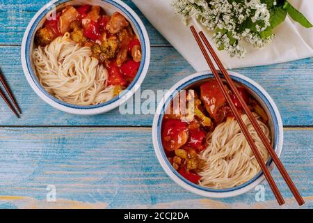 Tagliatelle di riso con pollo fritto in padella e verdure in ciotole e bastoncini. Vista dall'alto. Foto Stock