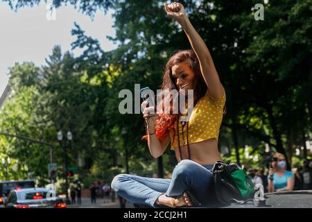 Portland, Stati Uniti. 22 agosto 2020. Una giovane donna si siede sulla cima di un'automobile che tiene una Bibbia. Gli aderenti alla Prati Boy e Patriot di destra, "Three-Percenters", e altri alleati armati dell'estrema destra hanno dimostrato a Portland, Oregon, il 22 agosto 2020 e sono stati incontrati da contromandanti, Antifa e sostenitori della Black Lives Matter. Entrambi i lati hanno fatto precipitarsi i detriti l'uno contro l'altro e hanno sfregato molte volte, ma non ci sono state lesioni gravi. (Foto di John Rudoff/Sipa USA) Credit: Sipa USA/Alamy Live News Foto Stock