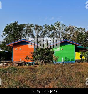 Due colorate cabine rustiche in legno dipinte in arancione luminoso e verde. Foto Stock