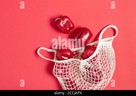 Peperone rosso in mesh bianca, borsa riutilizzabile, vista dall'alto. Concetto di shopping ecologico. Mangiare sano. Foto Stock